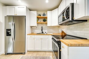 Eine moderne Küche mit weißen Schränken, Edelstahlgeräten und Holz Arbeitsplatten.