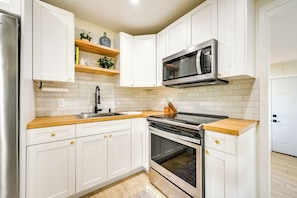 A modern kitchen with white cabinets, a stainless steel refrigerator, a microwave, and a stove. - Modern 2-unit Combo w/ Pool: 'naples Hideaway' (Naples)