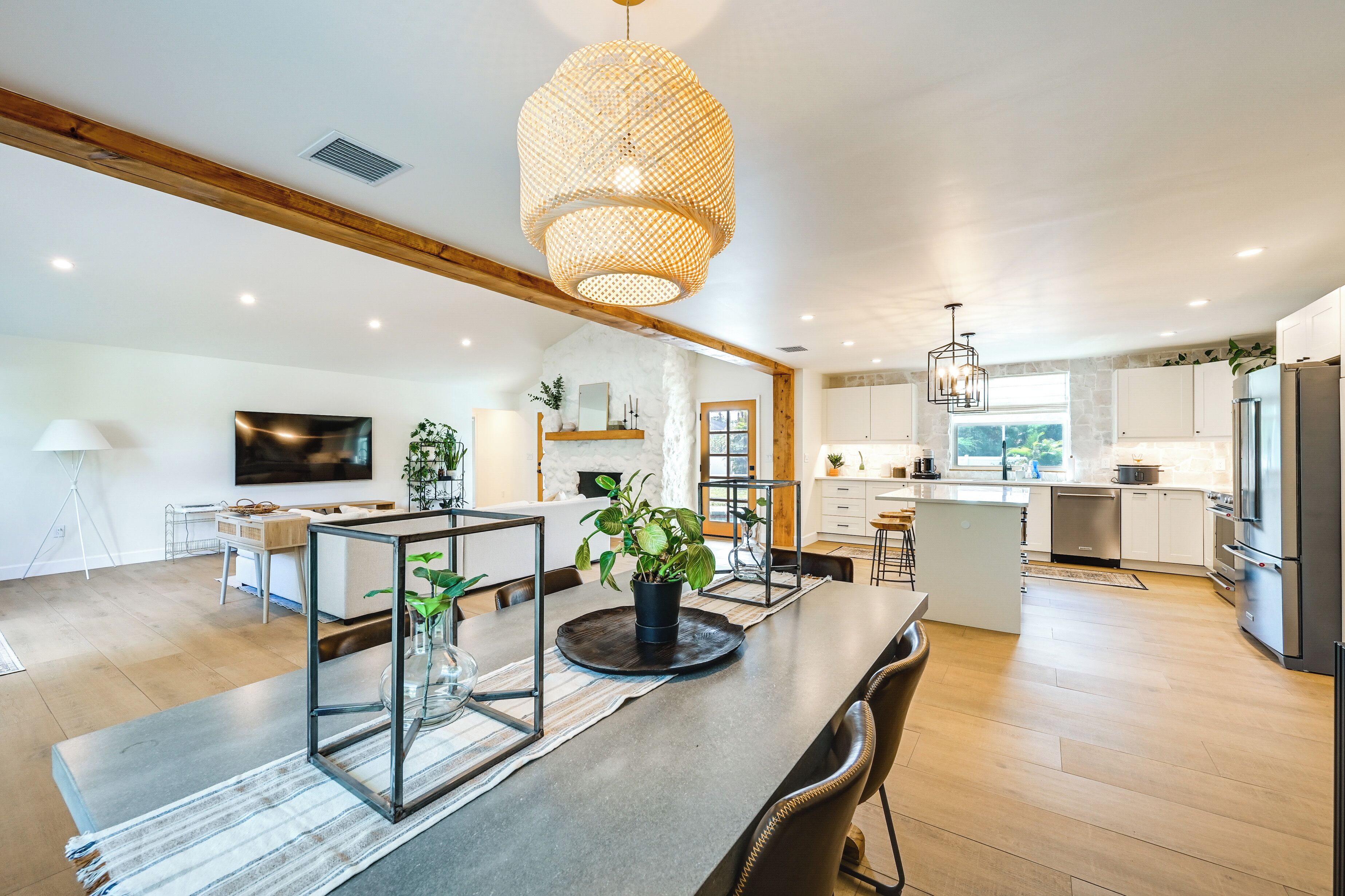 A modern kitchen with a central island, wooden beams, and a large pendant light.