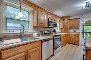 A kitchen with wooden cabinets, stainless steel appliances, a granite countertop, and a window with a view of greenery. - Fire Pit & Lake Access! Crossville Group Escape (Crossville)