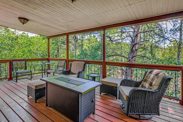 Un espace extérieur abrité, doté d’une table et de chaises, et entouré d’arbres.