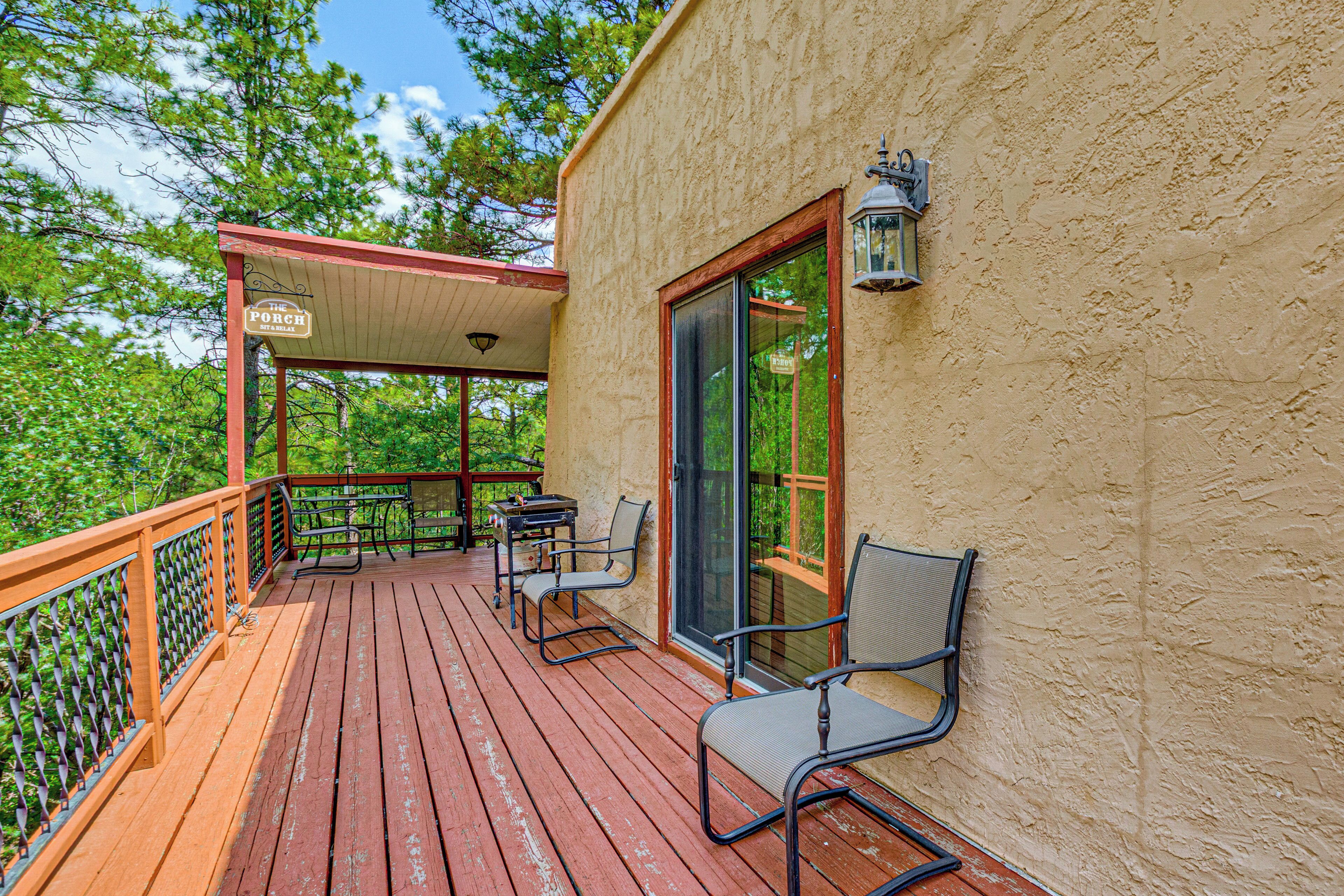 A wooden deck with outdoor seating, a covered area, and a building with a textured wall.