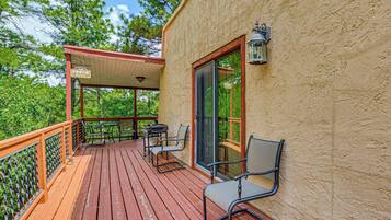 A wooden deck with outdoor seating, a covered area, and a building with a textured wall.