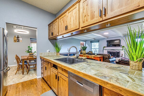 A kitchen with wooden cabinets, a granite countertop, and a dishwasher. - Shuffleboard & Arcade! Alto Family Escape (Alto)