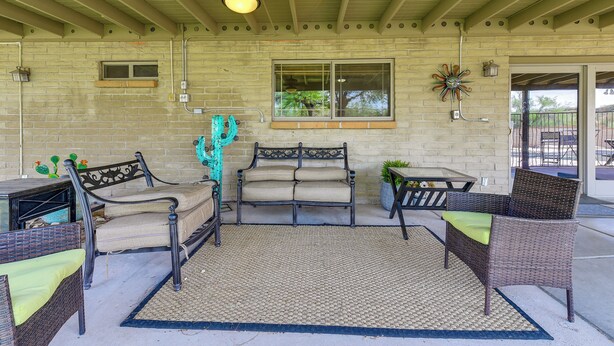 A covered patio area with seating arrangements, a ceiling fan, and a window with a view. - Game Room, Playset! Family-friendly Tucson Getaway (Tucson)