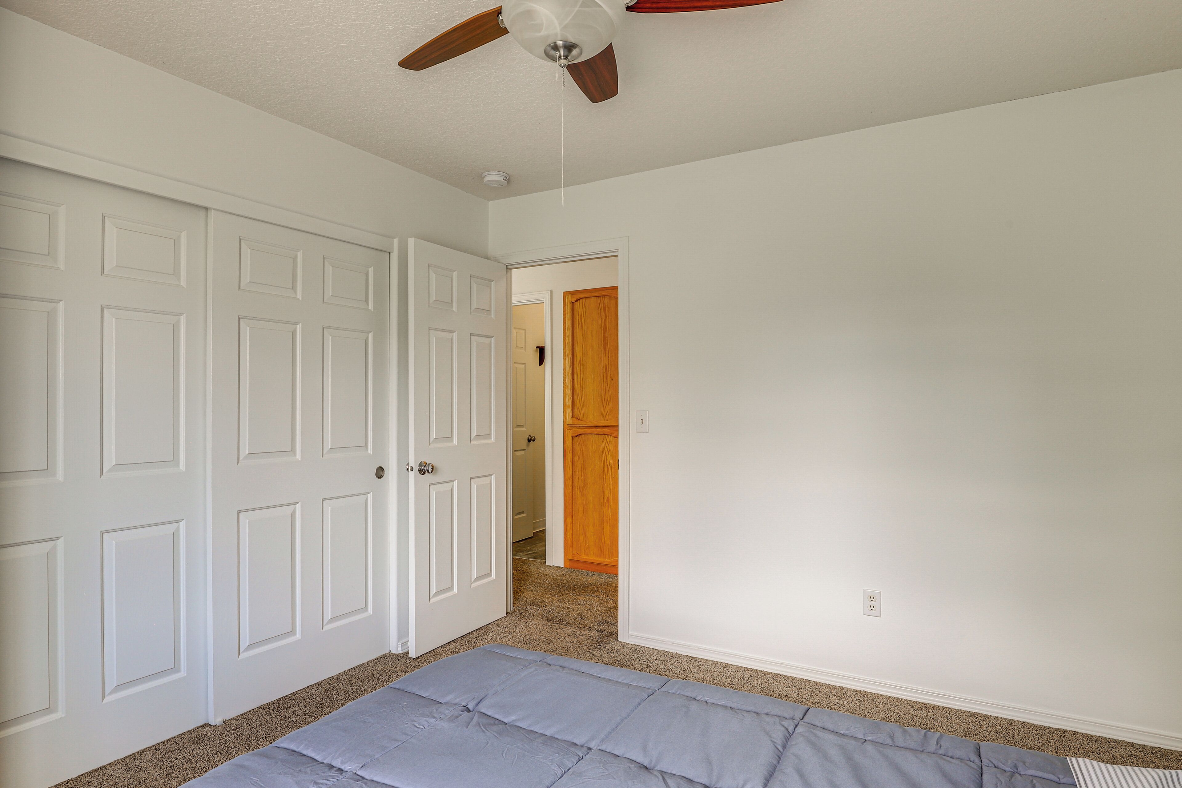 A room with white walls, a ceiling fan, and a carpeted floor.