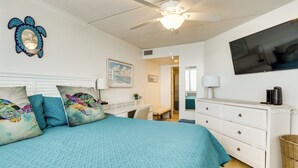 Ein Schlafzimmer mit einem Bett, einem Schreibtisch, einer Kommode, einem Deckenventilator und einem Fernseher.
