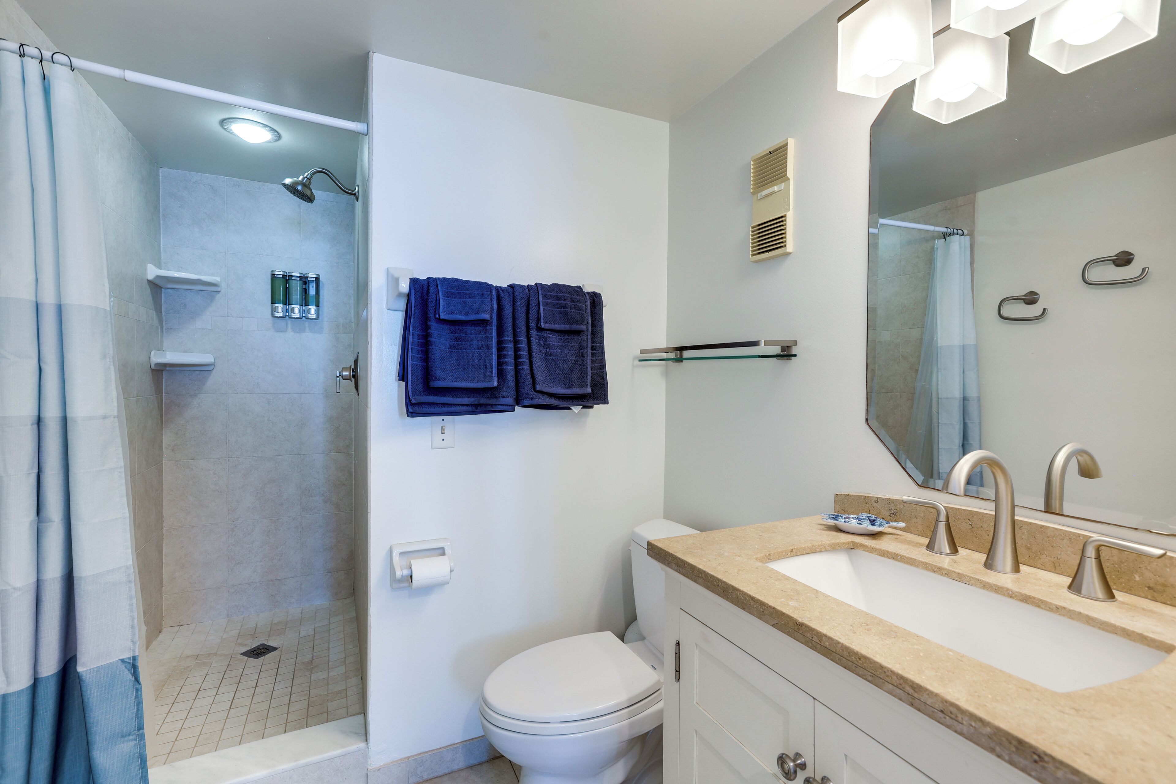 A modern bathroom with a shower, toilet, and sink.