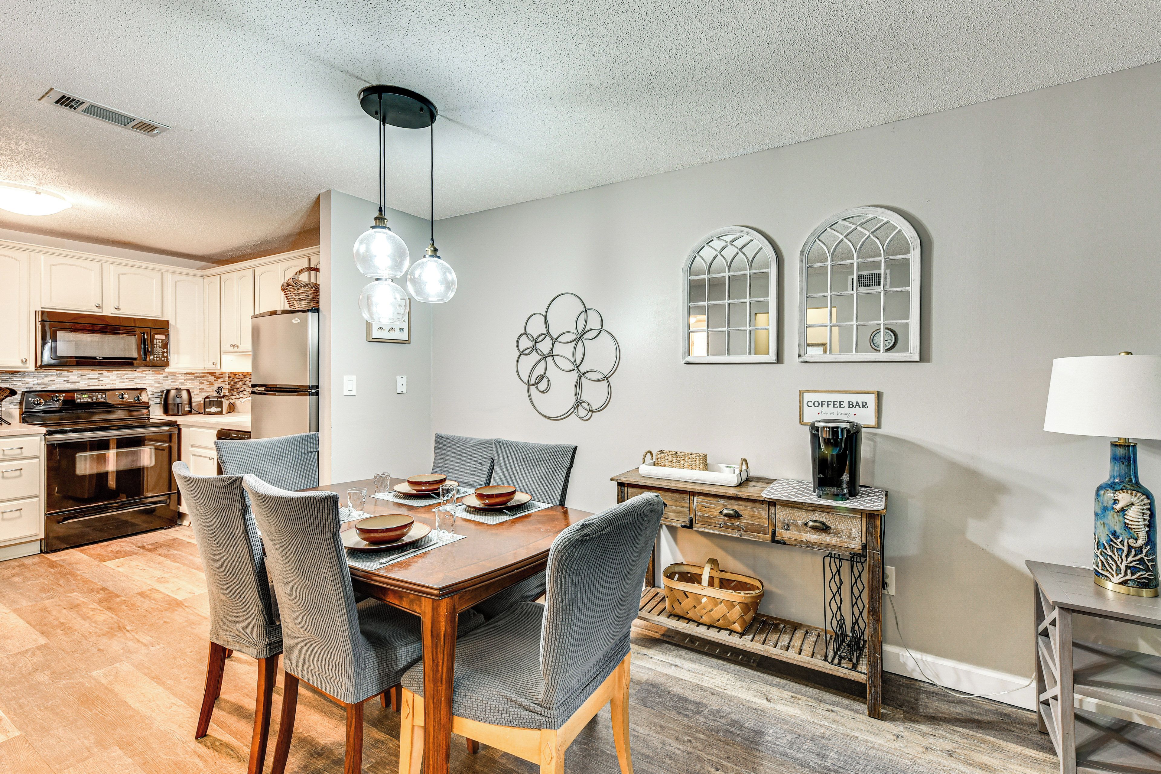 A dining area with a wooden table, chairs, and a kitchen in the background.