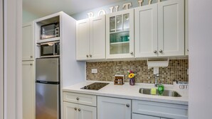 A kitchen with white cabinets, a stainless steel refrigerator, a built-in oven, and a tiled backsplash. - 1 BR Ocean Inlet View With Private Pool (Murrells Inlet)