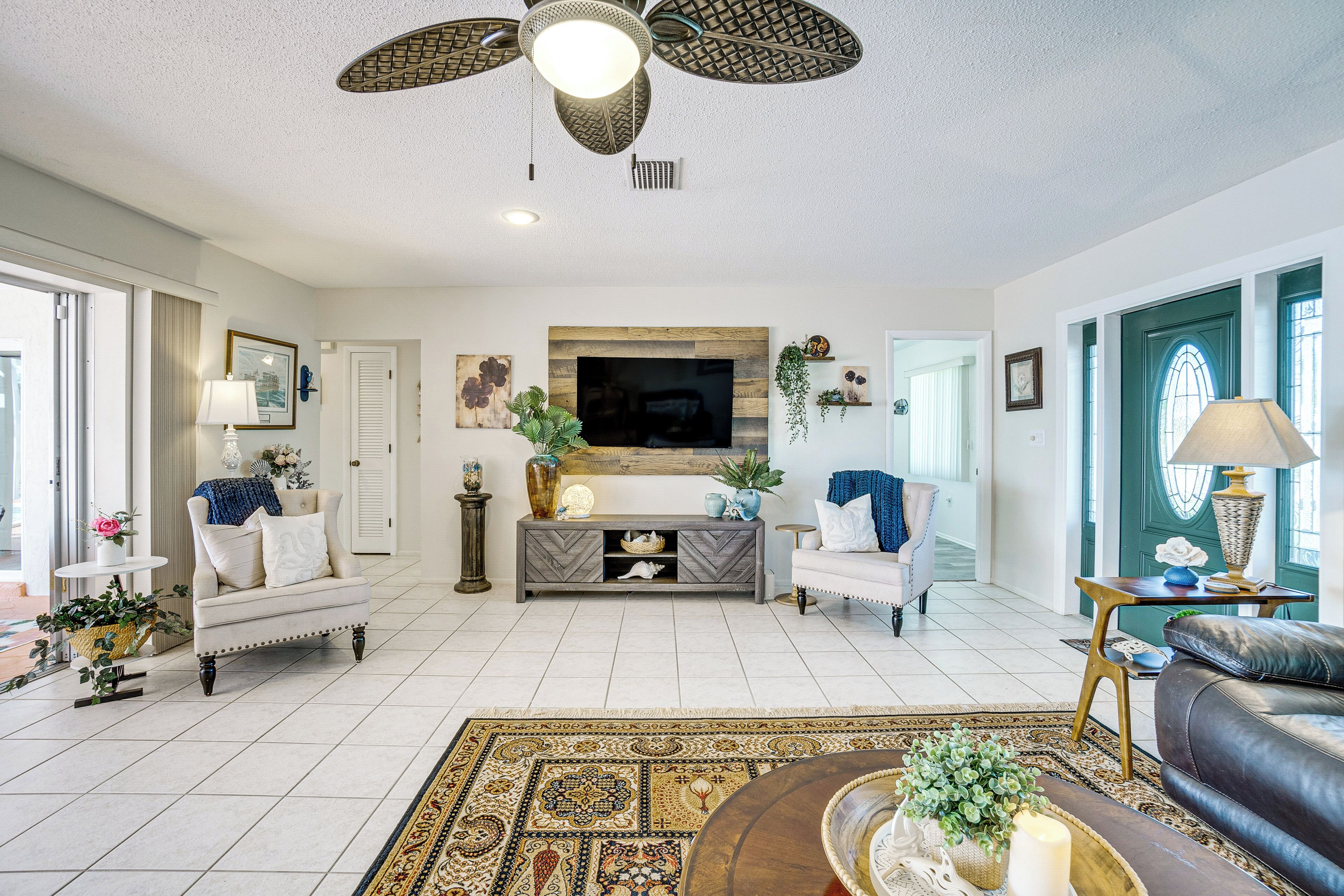 A living room with a fireplace, a television, and a ceiling fan.