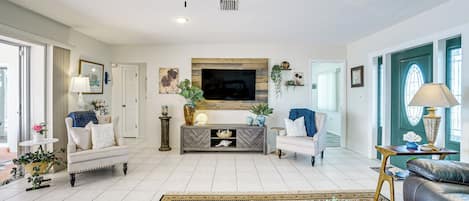 A living room with a fireplace, a television, and a ceiling fan.