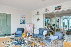 A living room with wicker furniture, a glass coffee table, and decorative pillows. - Pool, Fishing Dock! Port Charlotte Canal-front Gem (Port Charlotte)