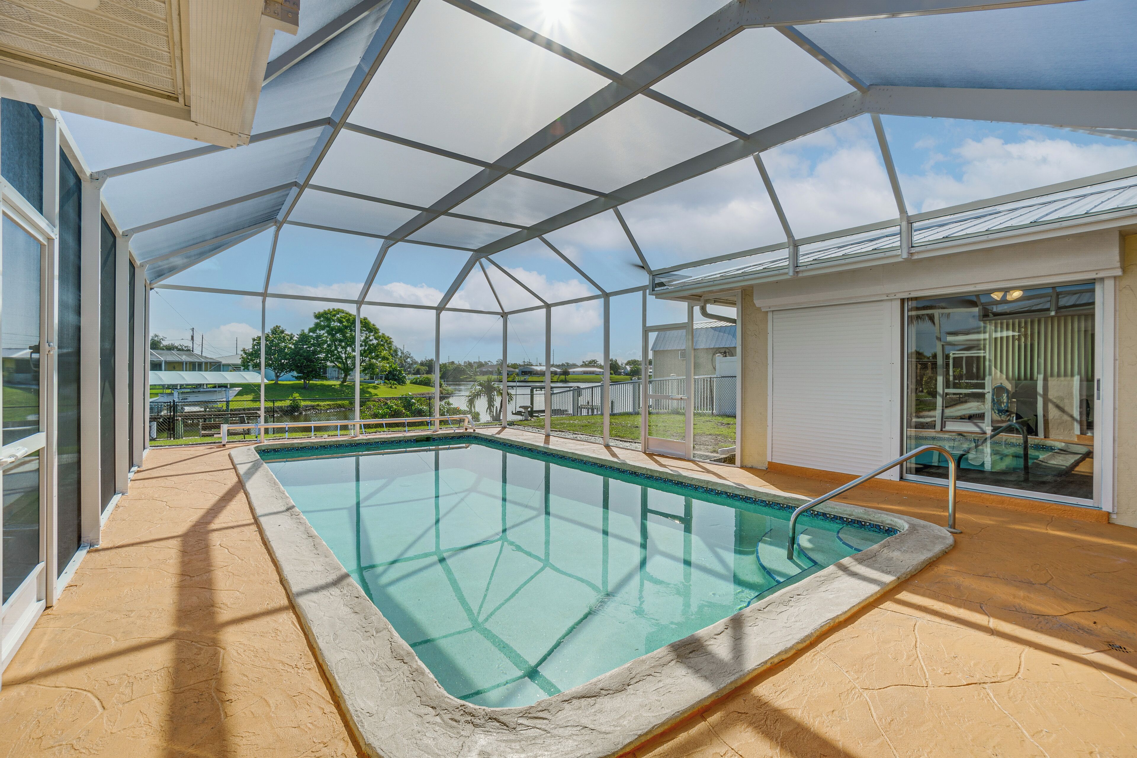 A covered swimming pool with a glass ceiling, surrounded by a concrete deck and a view of the landscape.