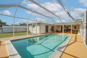 An indoor swimming pool with a glass enclosure, a covered patio area, and a view of the backyard. - Pool, Fishing Dock! Port Charlotte Canal-front Gem (Port Charlotte)