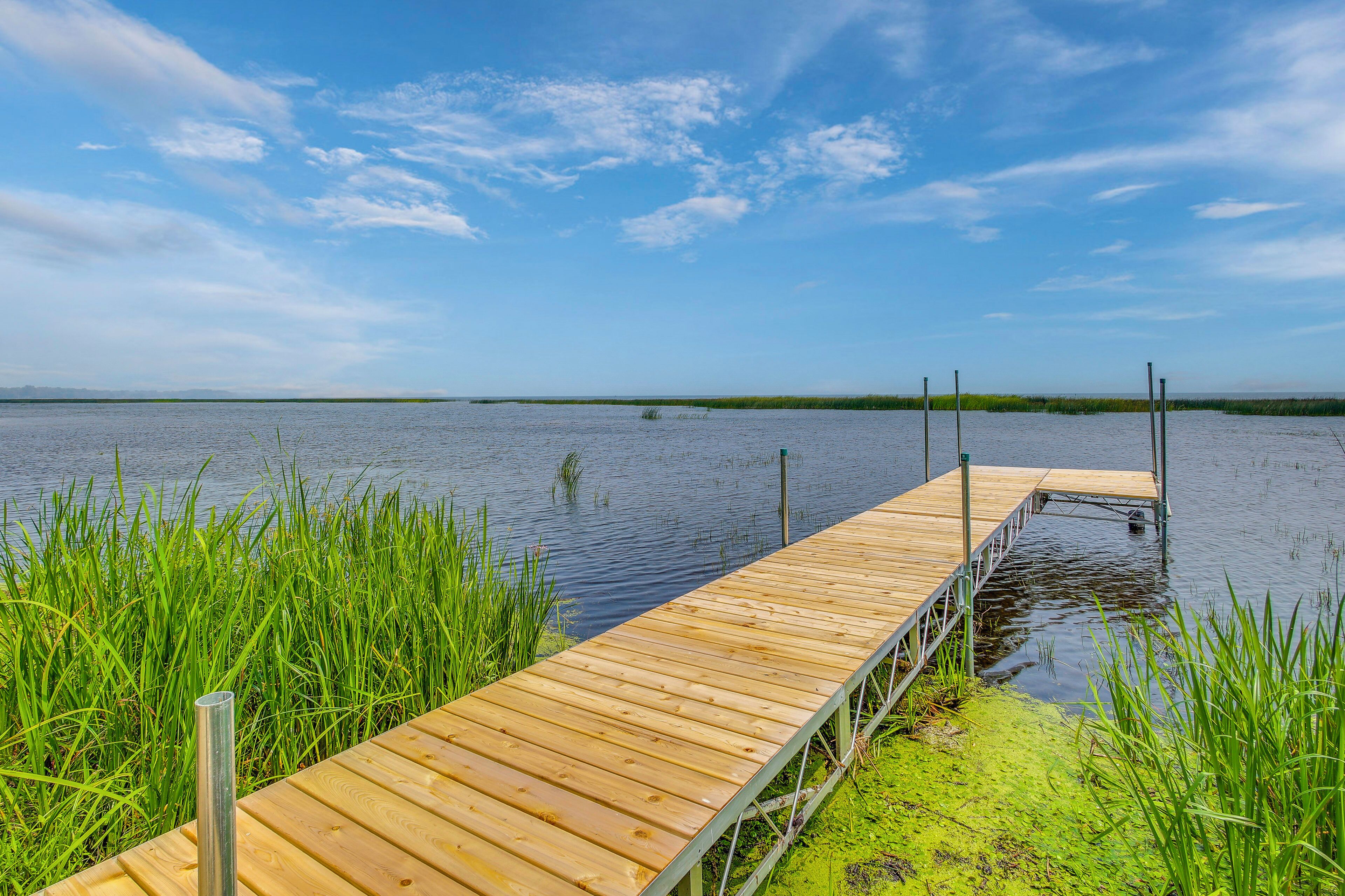 Un muelle de madera se extiende sobre aguas tranquilas, rodeado de exuberante vegetación.