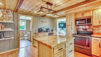 A kitchen with wooden cabinets, a central island, stainless steel appliances, and a coffee bar sign.