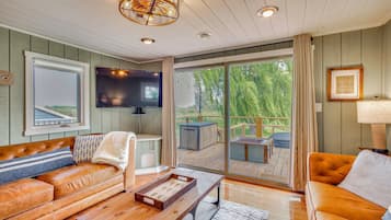 A cozy living room with a leather sofa, a wooden coffee table, and a large window offering a view of the outdoors.