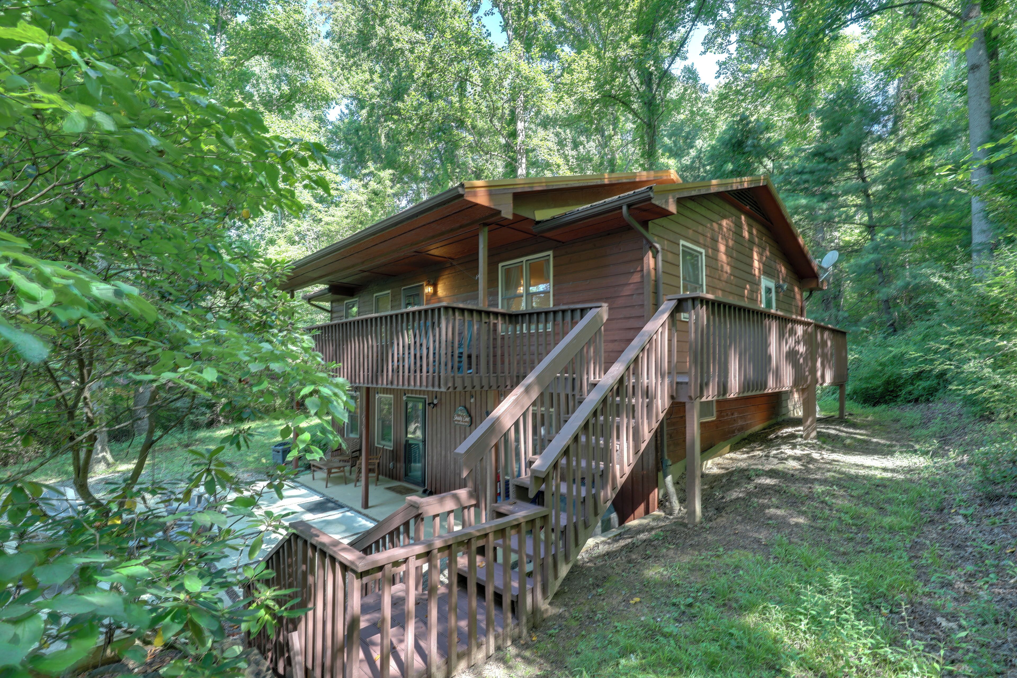 A cabin with a deck, surrounded by trees.