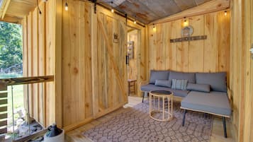 A wooden interior with a sofa and a small table, a rustic ceiling, and a wooden door.
