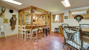 A rustic interior with a wooden bar, multiple stools, and a large mirror. - Cookout Patio w/ Fireplace! Norfork Lake Cabin (Elizabeth)