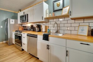 A modern kitchen with stainless steel appliances, white cabinetry, and a wooden countertop. - Cookout Patio w/ Fireplace! Norfork Lake Cabin (Elizabeth)