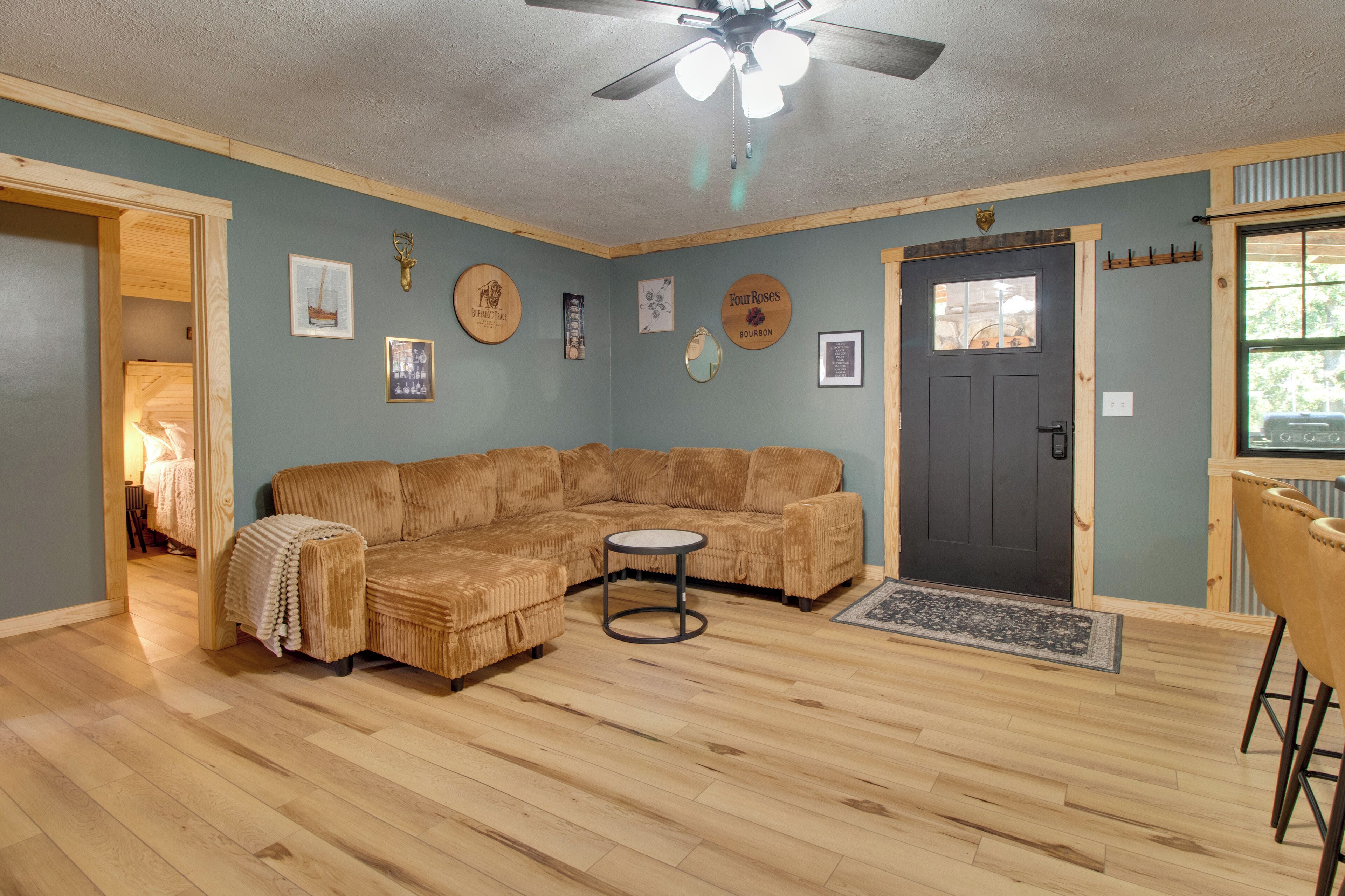 A living room with a sectional sofa, a round coffee table, a ceiling fan, and a door with a window.