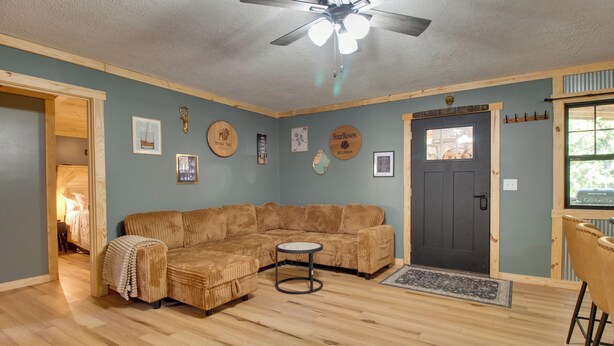 A living room with a sectional sofa, a round coffee table, a ceiling fan, and a door with a window. - Cookout Patio w/ Fireplace! Norfork Lake Cabin (Elizabeth)