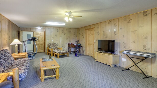 A living room with a sofa, a coffee table, a TV, a keyboard, and exercise equipment.