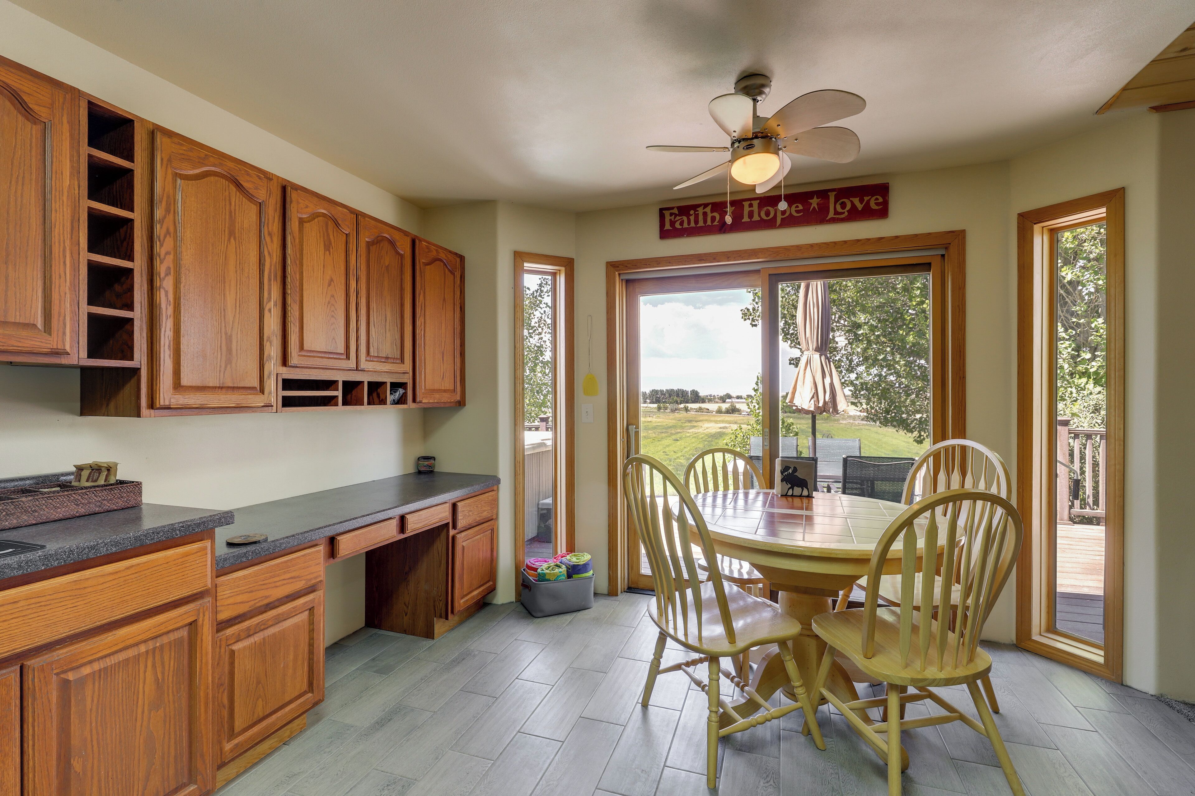 A kitchen with wooden cabinets, a granite countertop, and a dining area with a table and chairs.