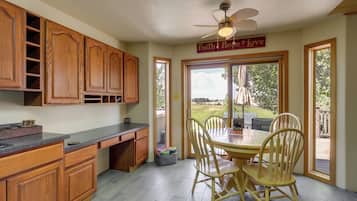 A kitchen with wooden cabinets, a granite countertop, and a dining area with a table and chairs.