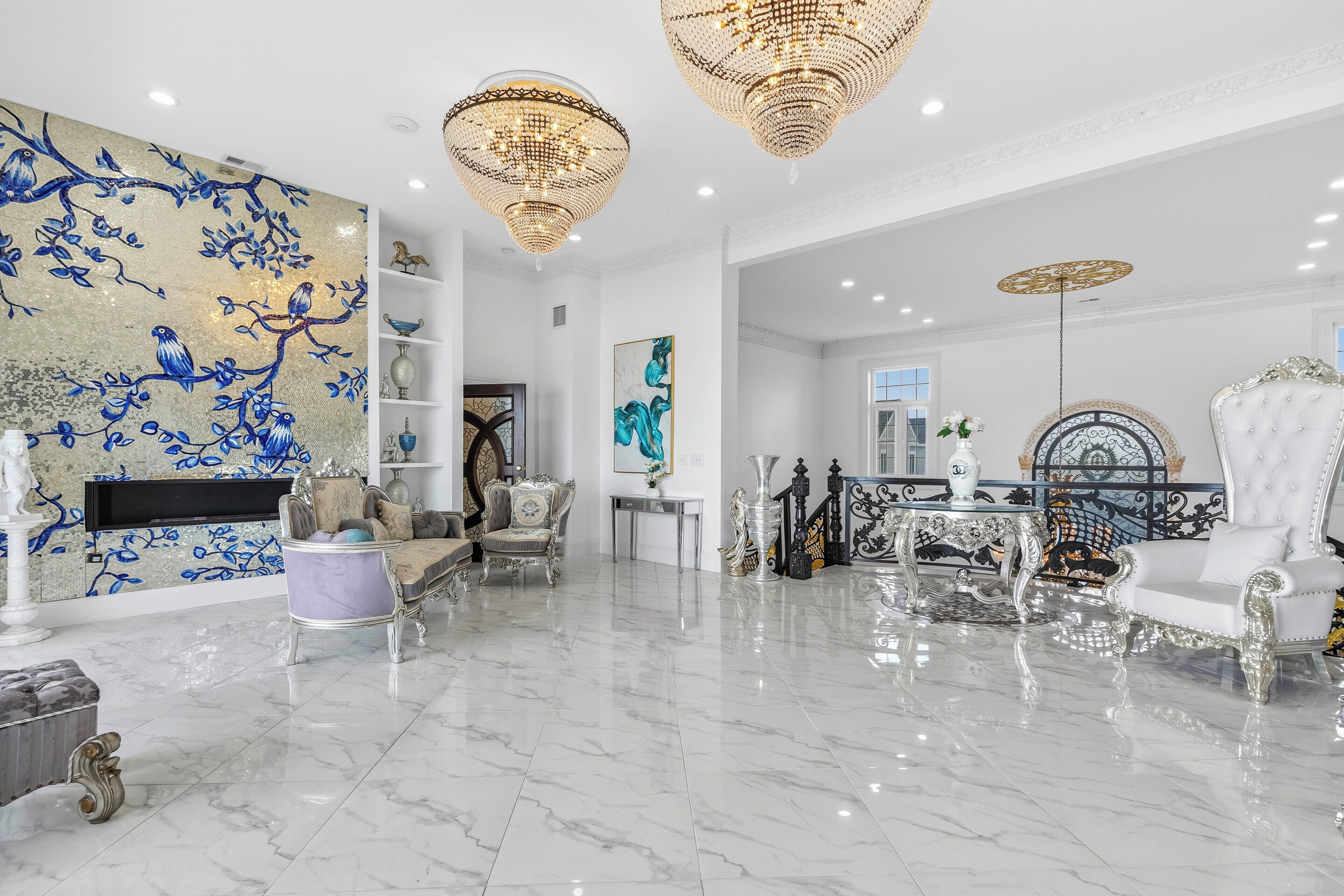 A luxurious living room with marble flooring, ornate furniture, and a large wall mural.