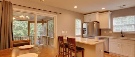 A modern kitchen with a central island, stainless steel appliances, and a dining area with a wooden table and chairs.