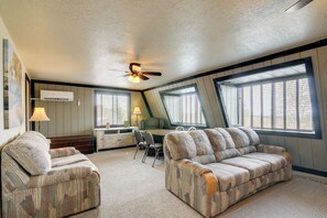 A spacious room with a ceiling fan, a desk with a chair, and two sofas.