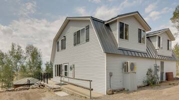 A two-story house with a sloped roof, a front porch with a railing, and a small attached garage.