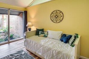 A bedroom with a bed, a wall decor, a lamp, and a view through a sliding door.