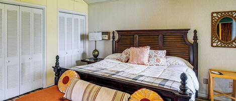 Un dormitorio con cama de madera, mesita de noche, lámpara, espejo y armario.
