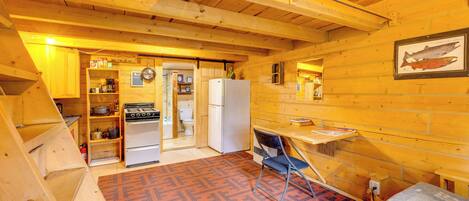A compact kitchen with wooden walls, a refrigerator, stove, and a sink.