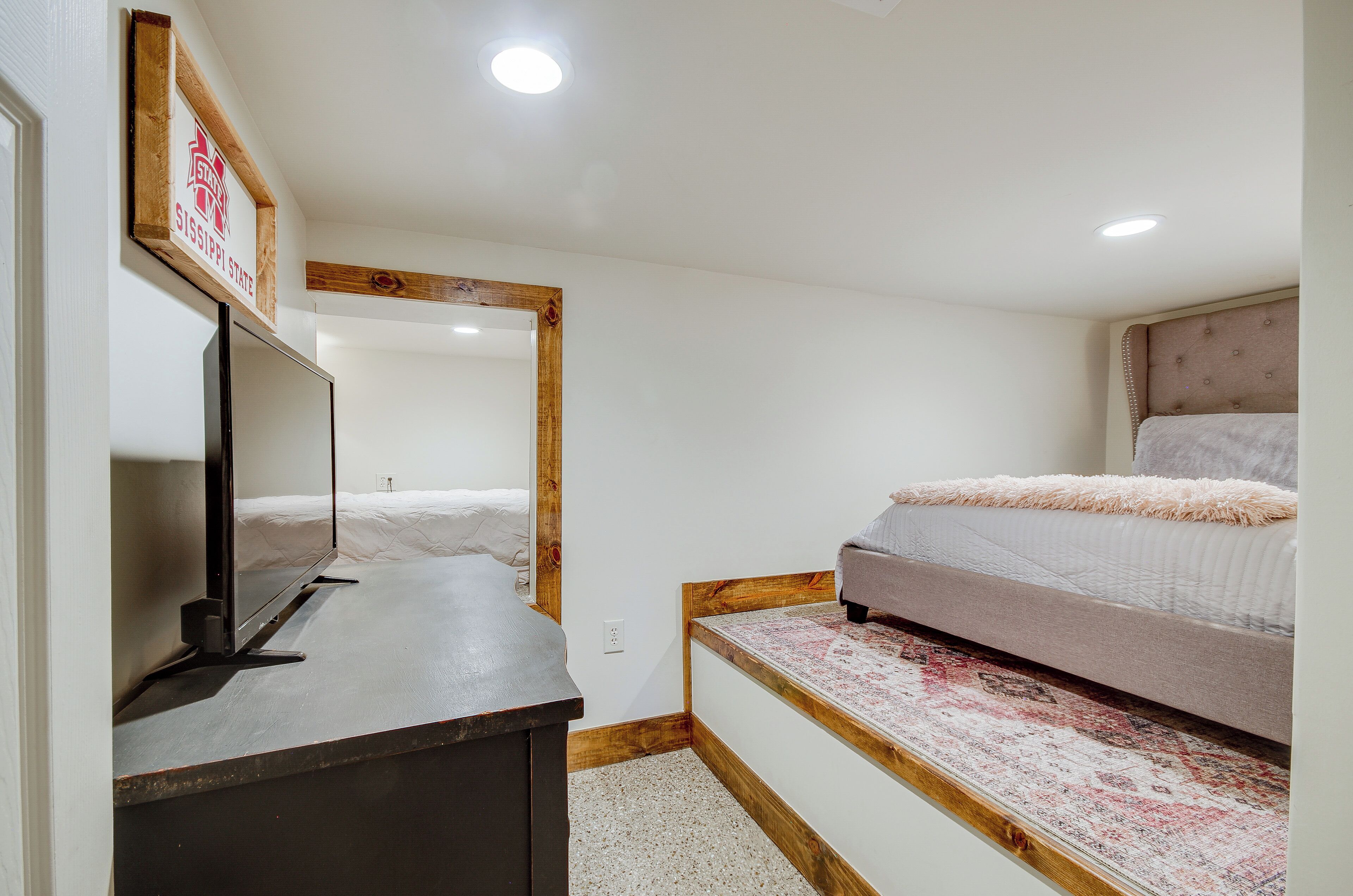 A bedroom with a bed, a TV, and a wooden headboard.