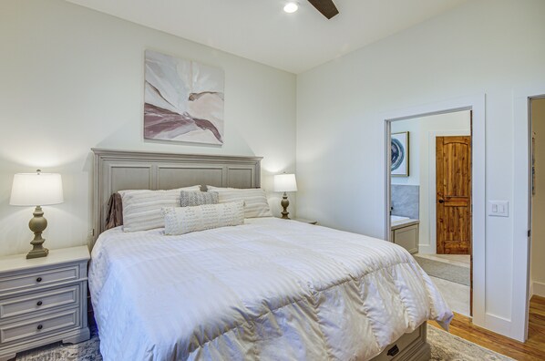 A bedroom with a large bed, two bedside tables with lamps, a wooden door, and a mirror.