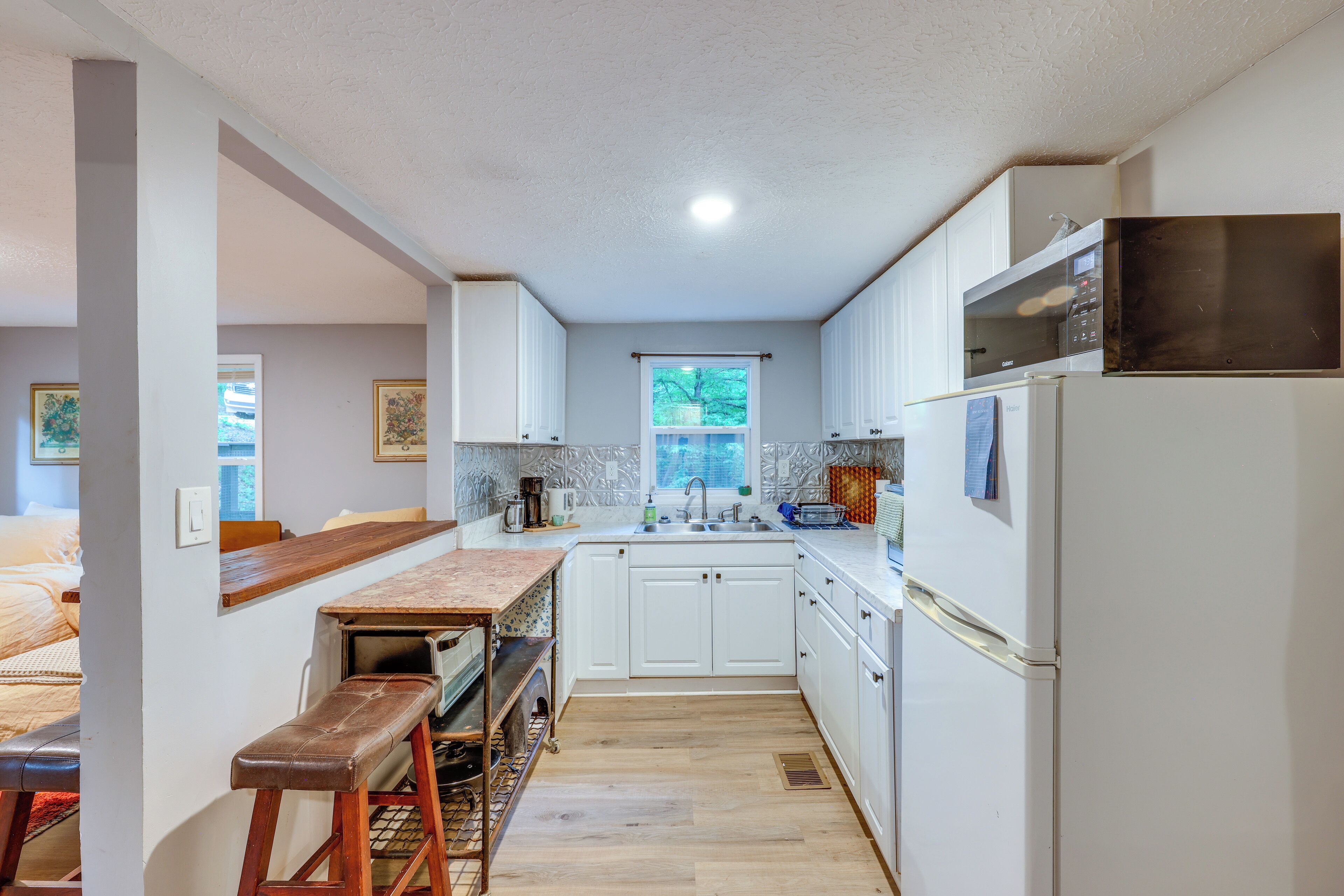 A compact kitchen with white cabinets, a wooden countertop, and a built-in microwave.