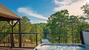 A hot tub with a wooden deck and a view of a lake surrounded by trees. - Lake Views, Big Deck, Hot Tub, Fire Pit, Game Room (Park Hill)