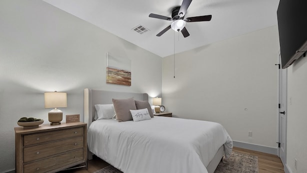 A bedroom with a bed, nightstands, a ceiling fan, a painting, and a door. - Lake Views, Big Deck, Hot Tub, Fire Pit, Game Room (Park Hill)