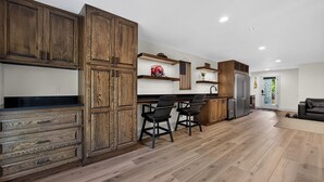 A modern kitchen with wooden cabinets, a black countertop, and a stainless steel refrigerator. - Lake Views, Big Deck, Hot Tub, Fire Pit, Game Room (Park Hill)