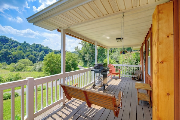 A wooden deck with a bench, a grill, and a view of a green landscape. - Cozy Cabin Retreat: Peaceful Mountain Views (Dungannon)