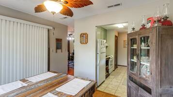 A kitchen with a wooden table, a ceiling fan, and a cabinet with glass doors.