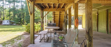 A covered outdoor area with a table, chairs, and a grill.
