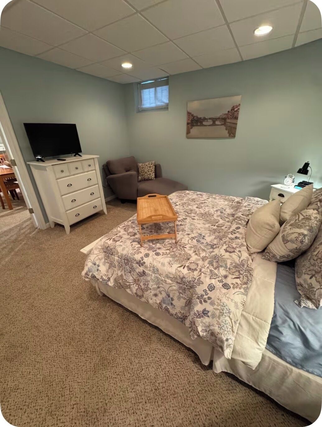 Quarto com cama, penteadeira, cadeira, mesa de cabeceira, televisão e janela.