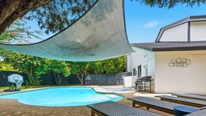 A backyard with a swimming pool, lounge chairs, a basketball hoop, and a barbecue grill. - Jungle Oasis - Pool + Hot Tub + Game Rooms (Richardson)