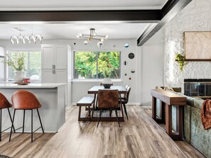 Uma cozinha moderna com área de jantar, piso de madeira e vista para o verde lá fora.
